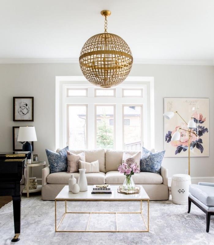 beyaz ve bej modern oturma odası dekor fikri, gri halı, bej ve mavi minderli keten kanepe, altın sarkıt lamba, mermer sehpa, duvar dekoru boyama