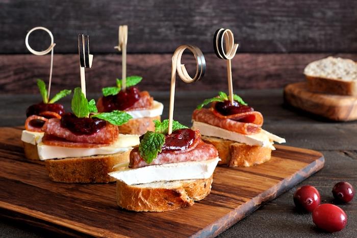 narezana bagetna novoletna predjed toast z briejem, italijansko klobaso in brusnično marmelado