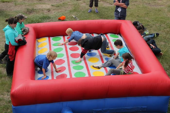 Çimlerin üzerinde renkli noktalar olan şişme bir twister'da açık havada twister oynama fikri, 5 yıl doğum günü