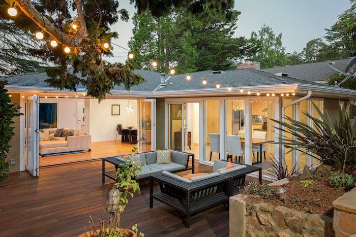 didžiulė namo pratęsimo idėja, gretimas pastatas atsiveria į medinę terasą su dviem mediniais suolais, išorinė šviesi girliandos apdaila