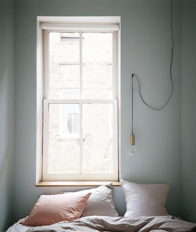 ideja za okrasitev spalnice za odrasle, majhen prostor, svetlo siva stena, sivo posteljnina, roza, svetlo sive in lososove blazine, viseča svetilka