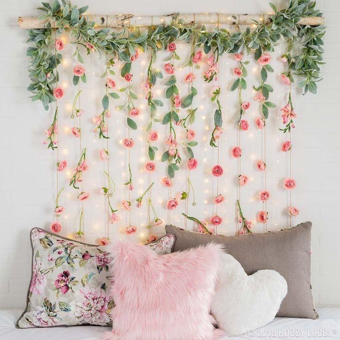 ahşap bir dal ve hafif çelenklerle asılı çiçek çelenkleri ile diy yatak odası dekor fikri orijinal başlık