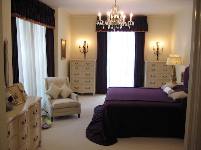 klasična postavitev spalnice za odrasle, starinsko pohištvo s predalniki in kristalni lestenec