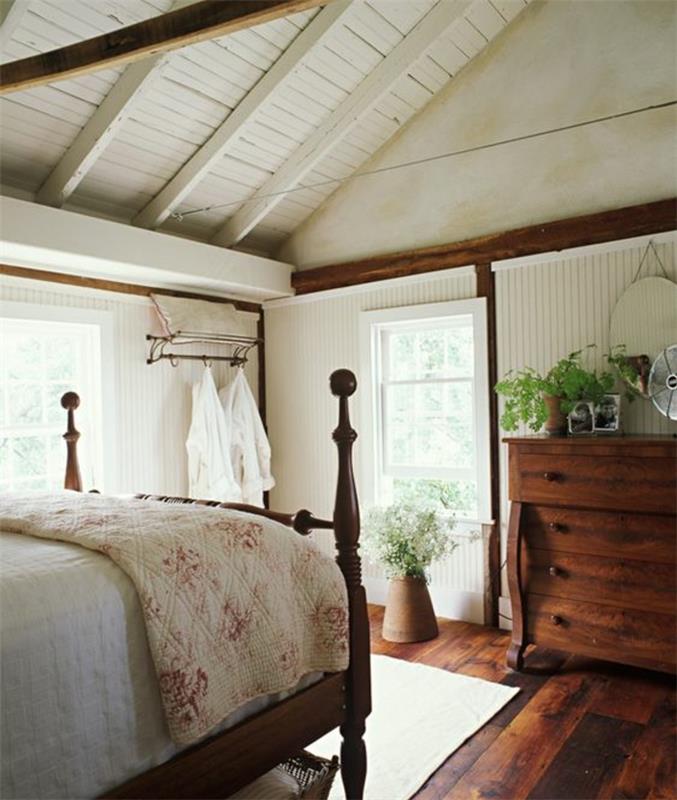 kako opremiti spalnico pod pobočjem, starinsko leseno posteljo, posteljno prevleko z vzorcem svobode, retro leseno komodo, lesena tla in izpostavljene tramove