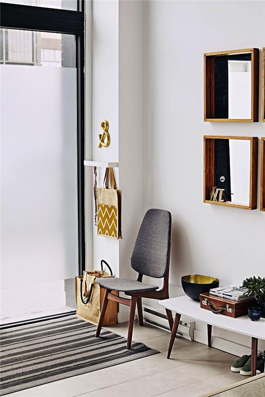 minimalistični vhod z majhno skandinavsko leseno -belo mizico, starinskim sivim stolom in ogledali z lesenimi okvirji