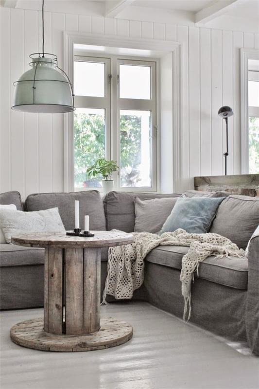 industrijsko deko v dnevni sobi, lesena klubska mizica, siv kavč, okrasne blazine, industrijske vzmetenja, bele obloge