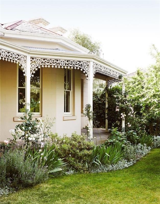 mažas, paprastas prancūziškas sodas su veja, gėlynu ir krūmais bei medžiais, kaimo stiliaus namas