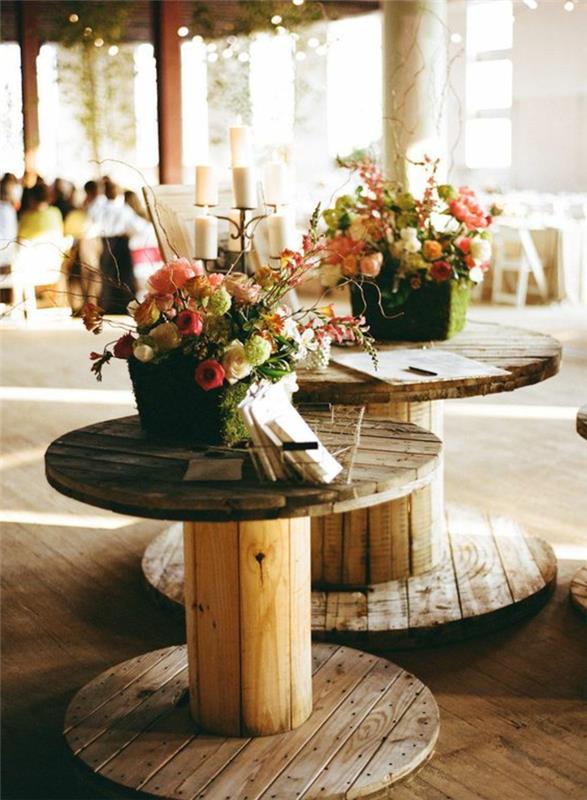 Deco stolp v slogu podeželskega sloga, mize iz surovega lesa in košare, napolnjene s šopki cvetja, postavitev pokrite terase