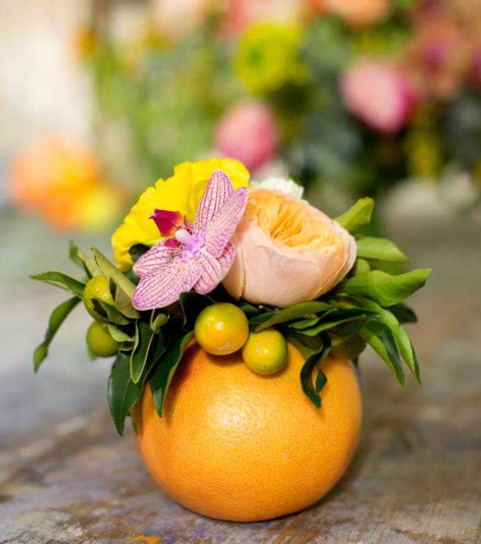 diy tropska poroka, izdolbena pomaranča z majhnim šopkom rož v njej, preprosta dekoracija poroke