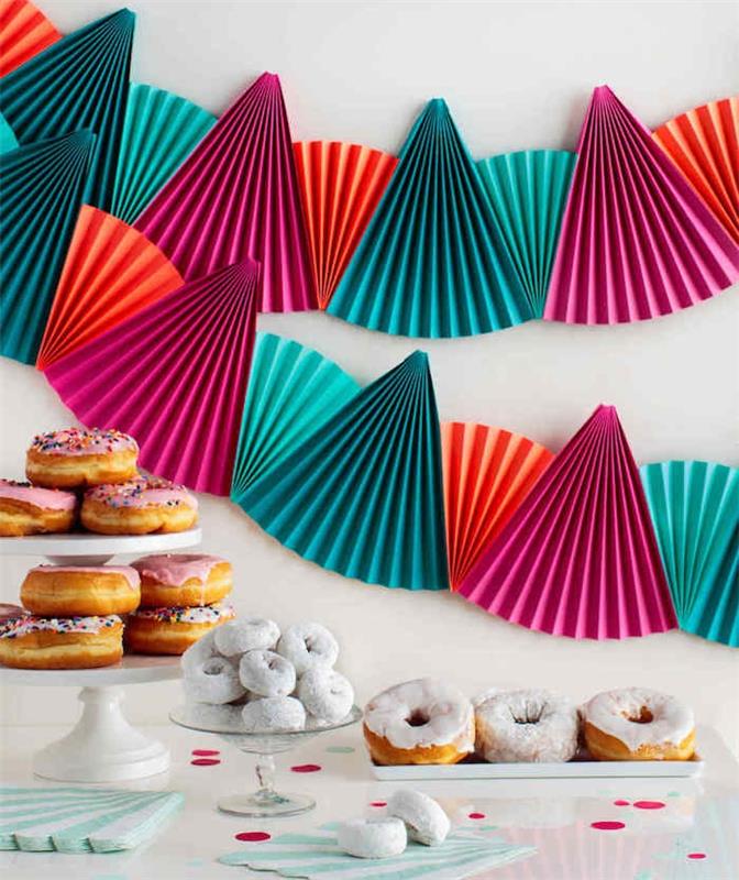 Donutlarda bir şeker çubuğunun arkasındaki beyaz bir duvarda renkli hayranlar yaratmak için doğum günü dekoru