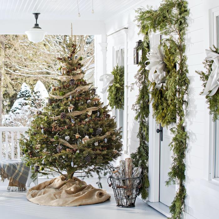 natūrali lauko Kalėdų dekoravimo idėja su egle ir šakomis, surinktomis ir kabančiomis aplink langus