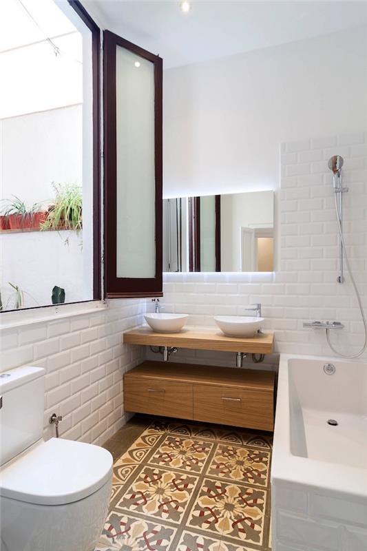 opremite majhno kopalnico z belimi stenskimi ploščicami in okrašenimi keramičnimi tlemi ter dvojnim okroglim umivalnikom in kadjo