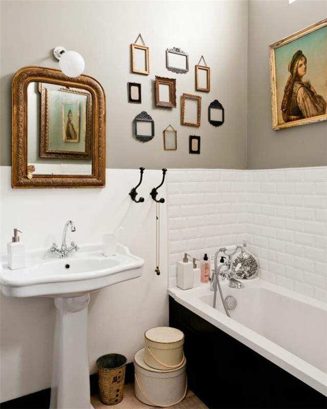 kopalnica v beli in sivi barvi, bele ploščice, umivalnik na podstavku, starinsko ogledalo, vgradna kad, deko, prazen okvir, več majhnih retro okvirjev za fotografije