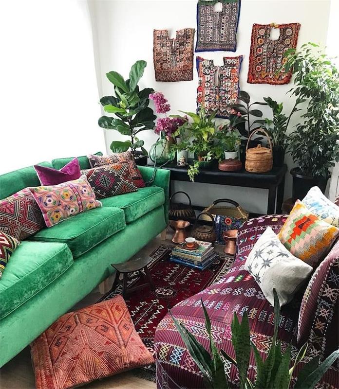 ideja tropske dnevne sobe z zelenim kavčem in bordo sedežno garnituro, okrašeno z vzhodnimi blazinami, orientalsko okrasnimi stenami, zelenimi rastlinami na tleh in na črni mizi za serviranje