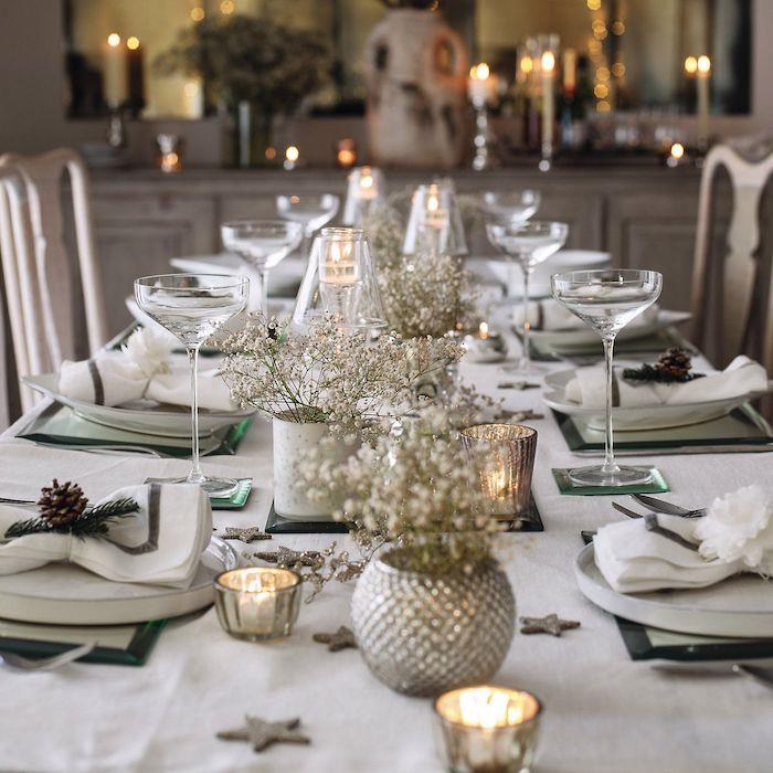 mini vazolarda küçük beyaz çiçek buketleri ile beyaz masa örtüsü, çam kozalakları ve çam dallarıyla süslenmiş peçeteler