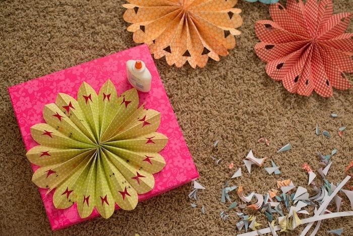 kako okrasiti darilni zavoj z ventilatorjem iz perforiranega papirja z vzorcem metulja, nekakšno okrasno rožo iz papirja