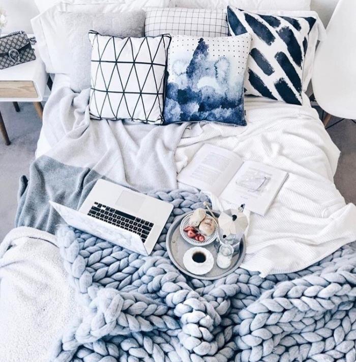 čakalnica s sivo, modro, belo posteljnino, okrasnimi blazinami, debelimi pletenimi kariranji, zajtrkom na pladnju