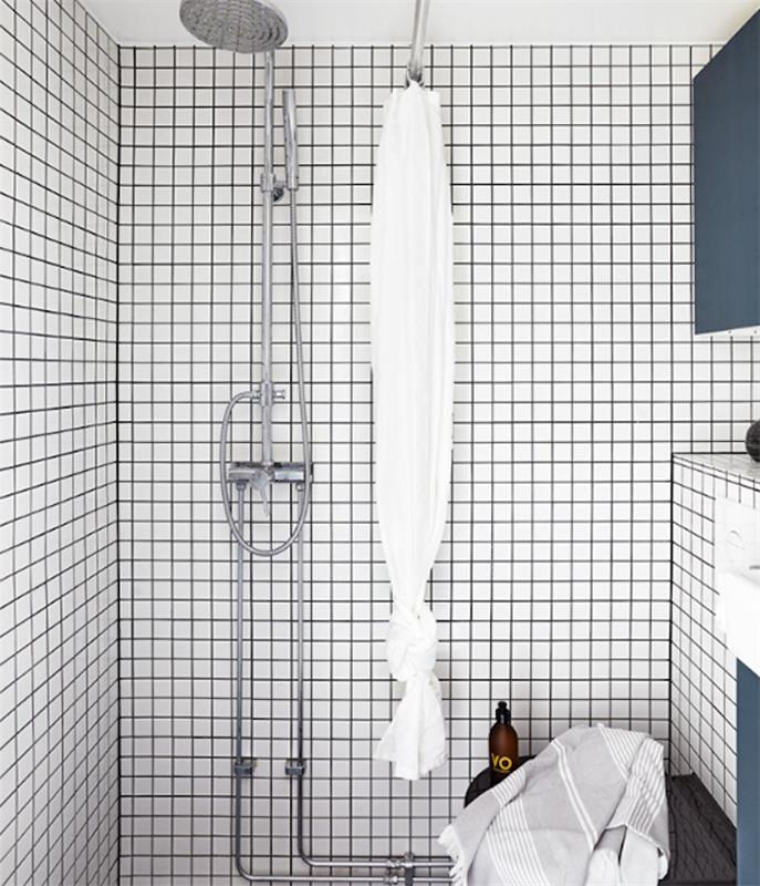 beyaz duvar karoları, gümüş duş ve mavi saklama üniteleri ile küçük tasarımcı banyo modeli
