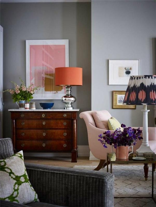 ideja dnevne sobe, stara lesena komoda, oranžna svetilka, roza miza, siva stena