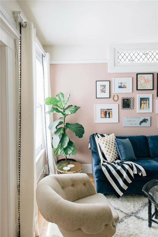 ideja dnevne sobe, maroška preproga, zelena rastlina, roza stena z več fotografijami in uokvirjenimi slikami