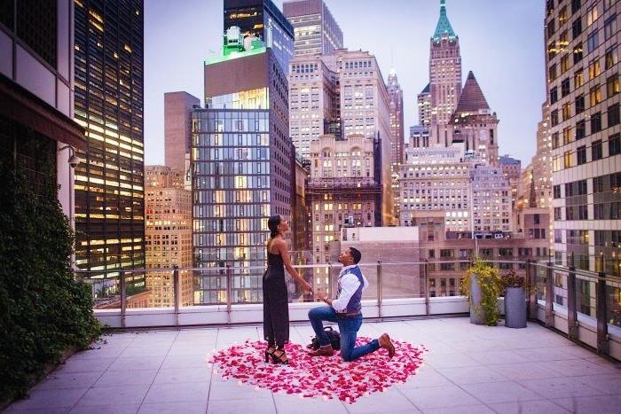 ideja presenečenja poroka na strehi stavbe, urbano okolje, okrog srca iz cvetnih listov vrtnic in sveč
