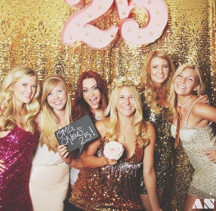 25 -ojo gimtadienio tema, šventinis vakaras blizgiomis suknelėmis, merginos su blizgučiais, blizgančios auksinės užuolaidos fonas, 25 numeris