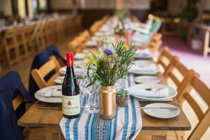 podeželski poročni dekor, vaze prebarvane v zlato barvo, podeželski šopek, namizni tekač v modro -beli barvi z ljudskimi vzorci na kmečki leseni mizi