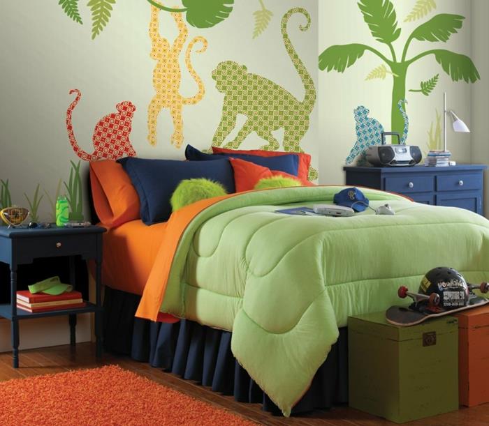 oranžinis kilimas, beždžionių tapetai, mėlyna ir žalia lova, spalvinga patalynė, berniuko miegamojo dekoras
