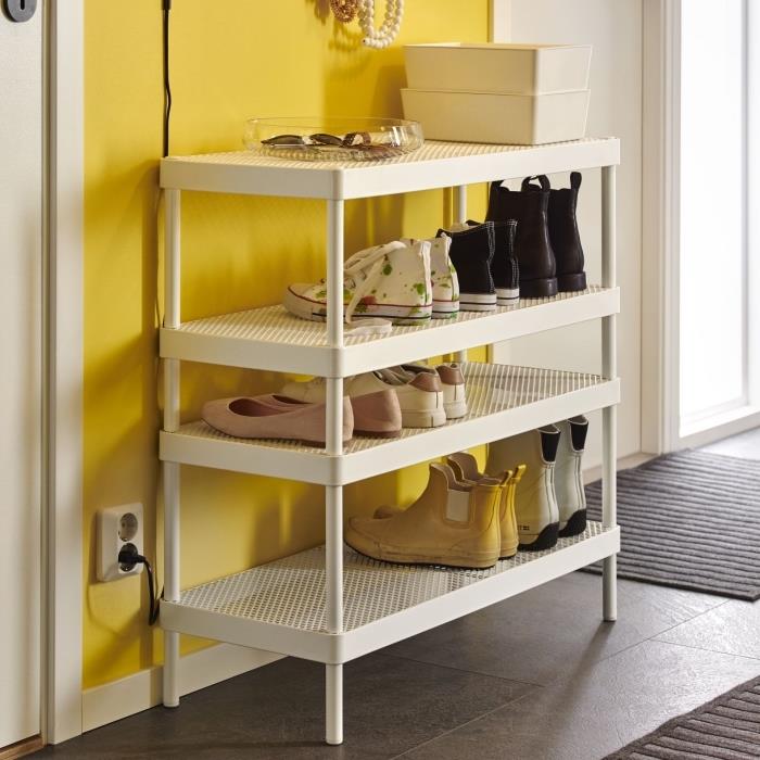 sarı duvarla hoş bir kontrast oluşturan dört seviyede delikli metalden güzel beyaz bir ayakkabı rafı