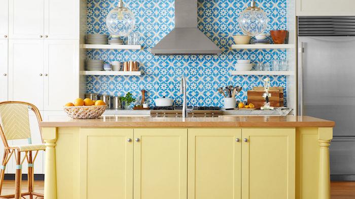 perdažykite virtuvės spintelę, pavyzdys centrinė sala perdažyta geltona spalva, pritaikytos plytelės su baltais ir mėlynais lipdukais, medinis stalviršis, baltos lentynos, rutuliniai pakabinami žibintai