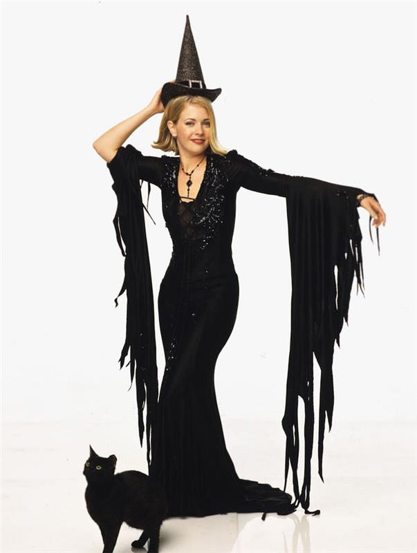 Genç cadı Sabrina cadı kılığına girmiş uzun siyah elbise ve kara kedi, 90'ların tarzı, cadılar bayramı için ünlü olmak için kıyafet