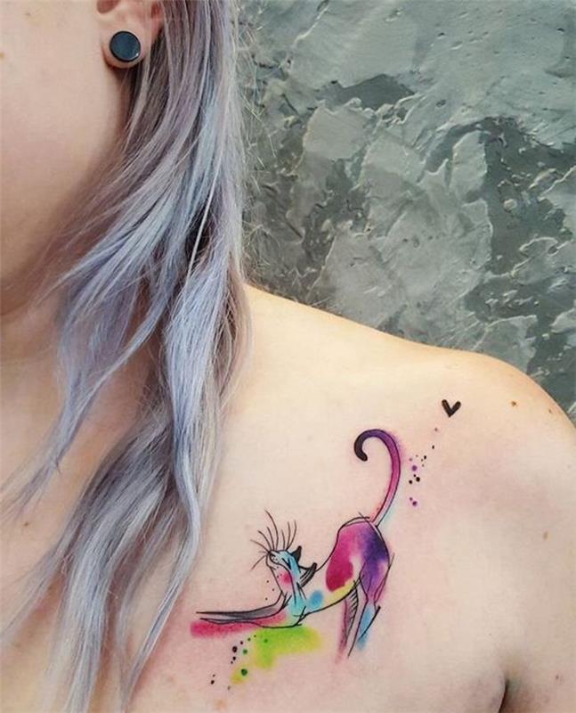 Akvarelna mačja tetovaža pod ključno kostjo mlade ženske, galaksijsko modri lasje