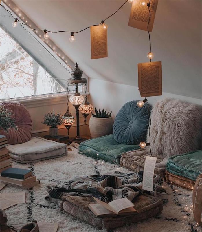 sėdynių pagalvėlės ant grindų ir dekoratyvinės rytietiškos pagalvėlės, beribis berbero kilimas, šviesi girlianda, miegamojo dekoras, knygų krūvos, svajonių miegamasis