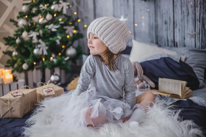 kompiuterio tapetų idėja jaukia Kalėdų tema, vaiko nuotrauka, apsupta kalėdinių dovanų priešais papuoštą eglutę