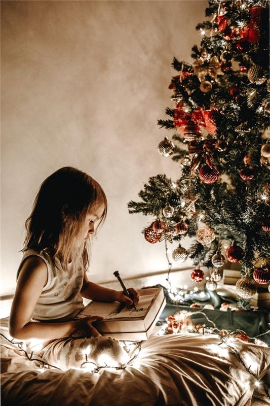 idėja, kaip papuošti medį raudonais ir auksiniais ornamentais, nuotrauka, kurioje maža mergaitė rašo savo laišką Kalėdų Seneliui