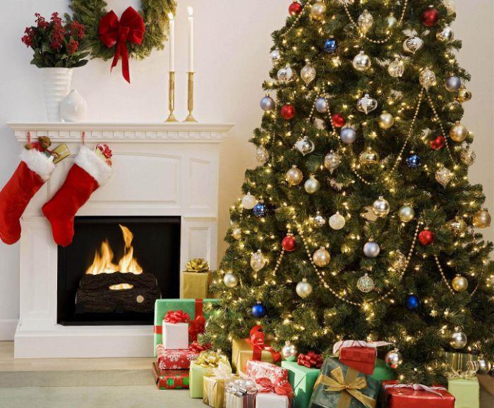 slika božično drevo z okraski božične kroglice zlato srebrno modro in rdeče več belih luči darila ob vznožju drevesa