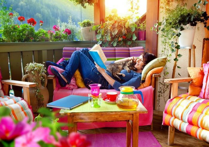 Gražios spalvos ir vaizdas iš terasos, moteris su katinu skaito knygą, apželdina nedidelį sodą, idėjos lauko terasoms gražiai papuošti