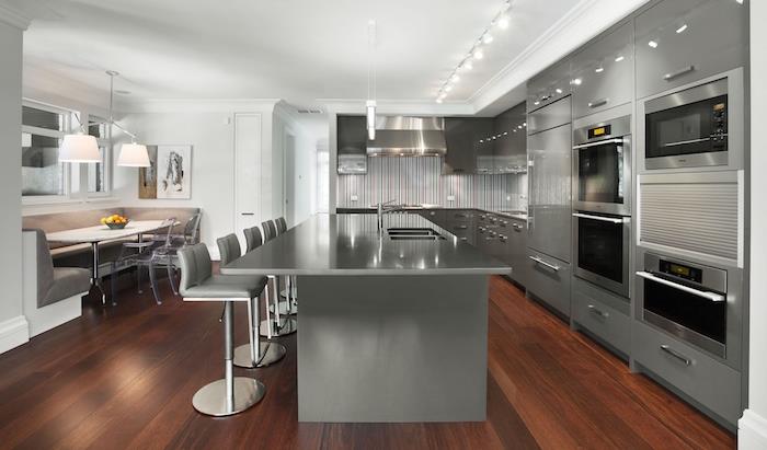 didelė pilka pro virtuvė su didele centrine sala, moderni betoninė pilka virtuvė ant tamsių medinių grindų