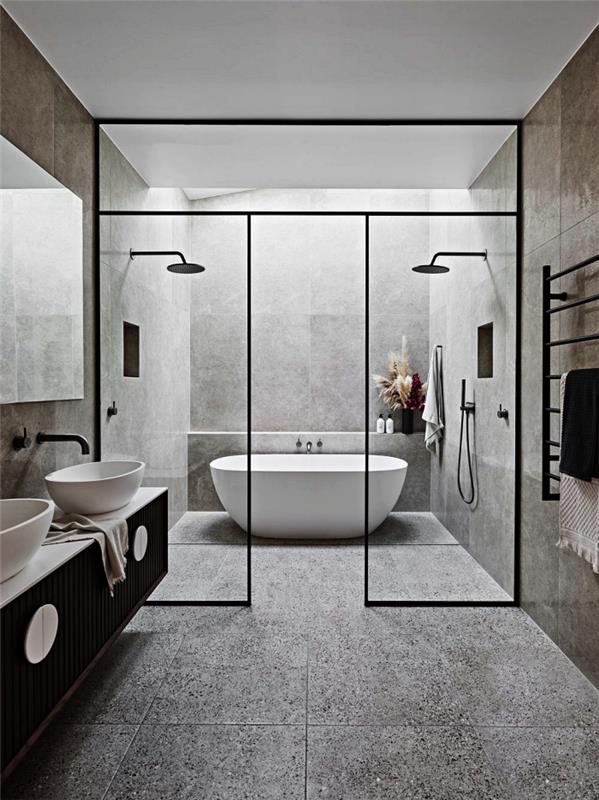 sodobna kopalnica iz ploščic s cementnim učinkom s tuši in samostoječo kadjo, omejeno s stekleno streho