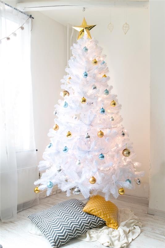 Altın, mavi ve gümüş renklerde küçük Noel topları ile süslenmiş, geometrik baskılı yastıklar ayak örtüsü ile süslenmiş beyaz Noel ağacı