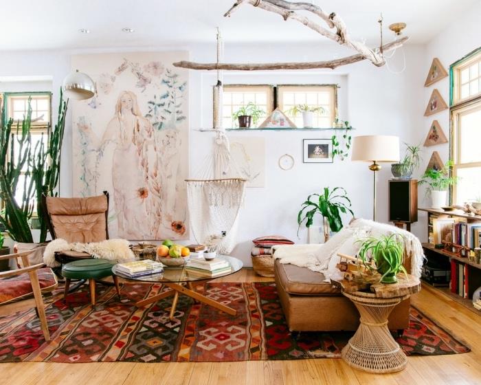 Boho prašmatnaus stiliaus atmosfera gyvenamajame kambaryje su baltomis sienomis su medžio parketu, spalvotu etniniu kilimu