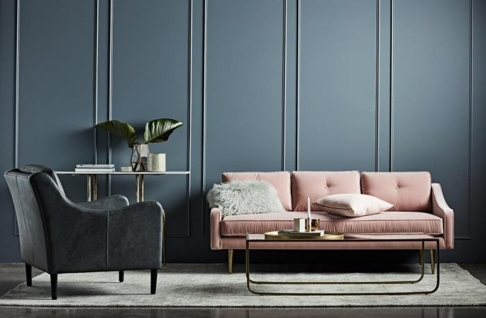 tamsaus gyvenamojo kambario dekoras su metalinio dizaino stalu kartu su pudra rožine sofa ir juodu odiniu foteliu ant šviesiai pilko kilimo