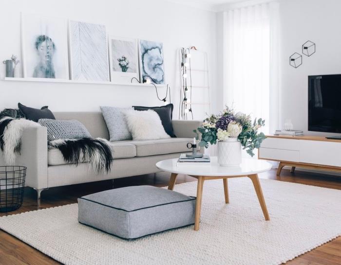 Skandinavska dnevna soba z dekorjem v kokonu, mizica in lesena tla, tkana bela preproga, siv sedež, siv kavč in okrasne blazine, lahek venec