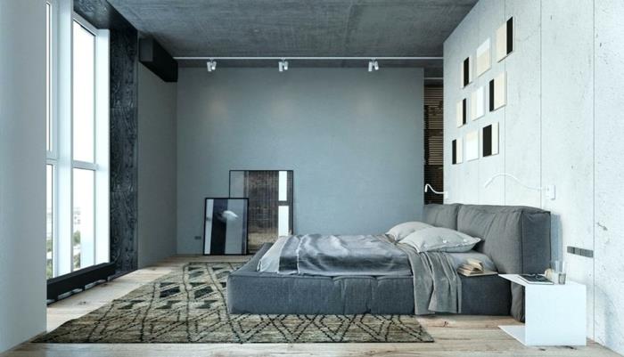 pilka povo siena miegamajame, pramoninis apšvietimas, rudas kilimas, lova su platforma