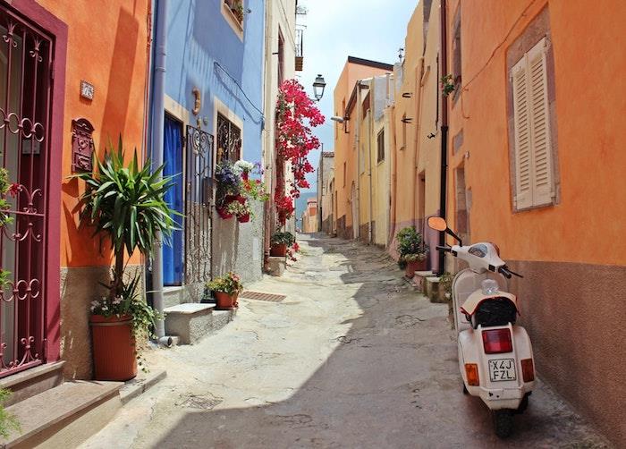 Bir adanın etrafında yürüyen bir vespa ile İtalya'da küçük sokak, arka plan görüntüsü, cennet gibi manzara, güzel renkli ev fotoğrafı