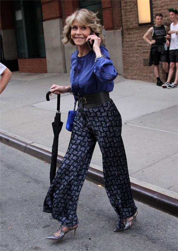 jane fonda ir jos suknelė lokk moteris 60 metų elegantiška su mėlynos spalvos kelnėmis ir juodais mėlynais marškiniais bei juodo diržo mados senute