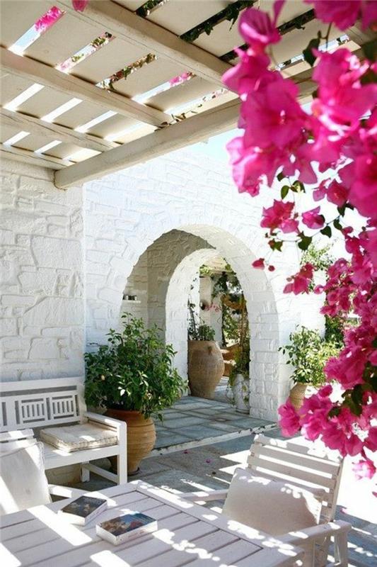 vrt-s-cvetjem-plezalna-rastlina-bela-kamnita-hiša-belo-vrtno pohištvo