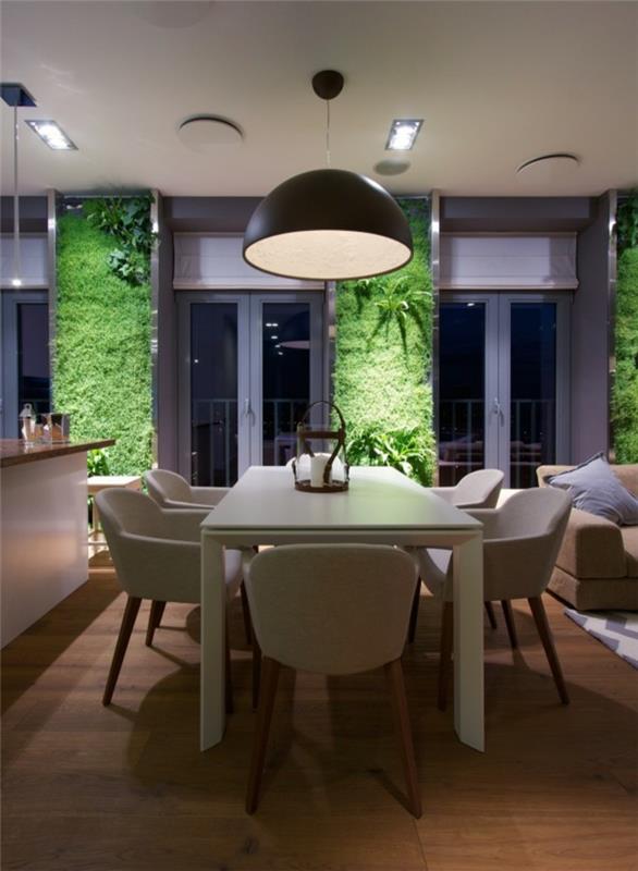 vertikalus sodas, juoda pakabinama lempa, žalios samanų sienos, baltas stalas ir baltos kėdės