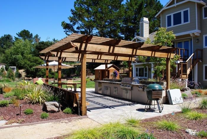 idėja, kaip sode įrengti vasaros virtuvę su medžio masyvo stogu ir betono bei nerūdijančio plieno moduliais