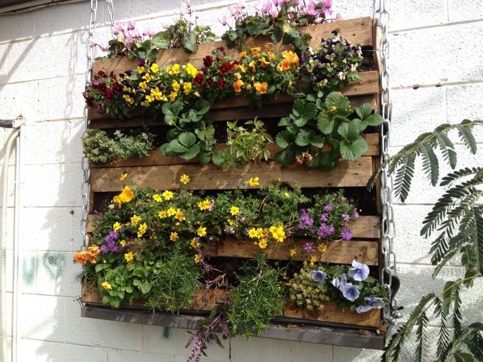 izvirna ideja za zeleno paletno steno, obešeno z verigo, sestavljeno iz različnih rož, za energijo sten balkona ali vrta